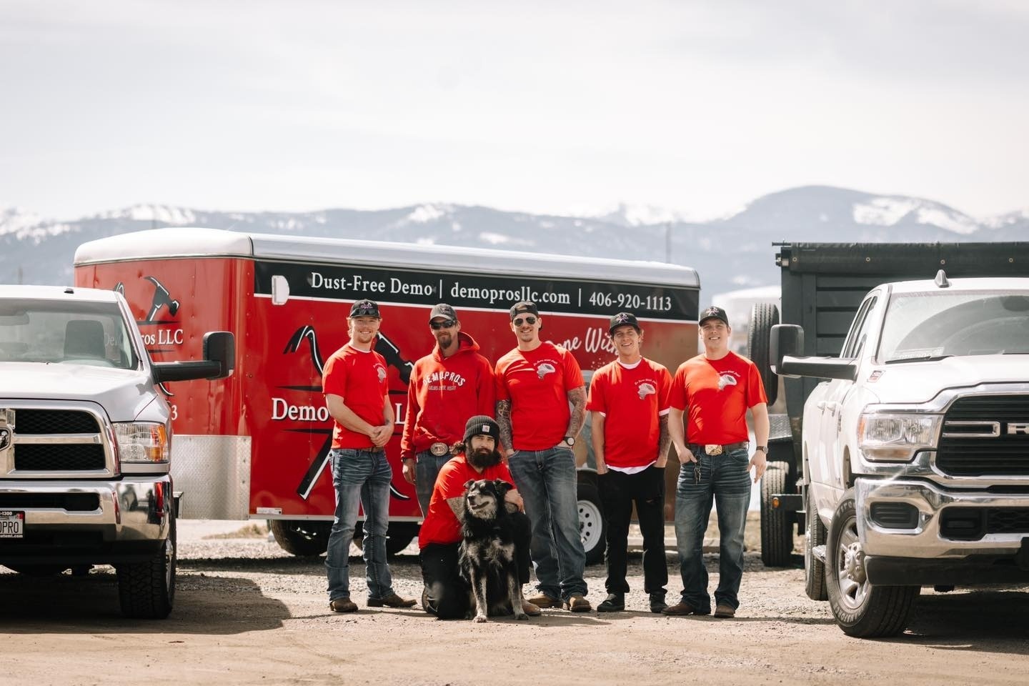 Demo Pros team with dog in front of Demo Pros branded trailer