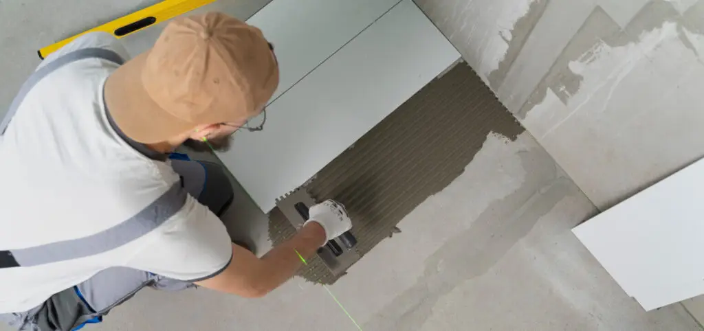 Finisher laying tile in a clean, debris-free space prepped by Demo Pros' dust-free demolition in a Montana renovation project.