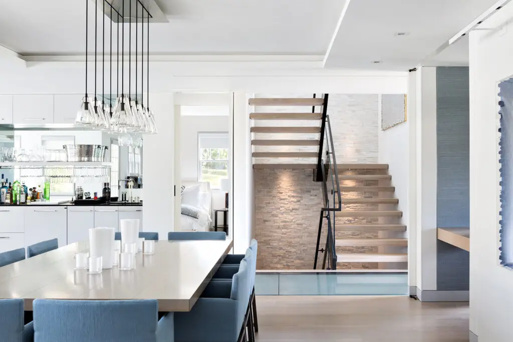 Modern open-plan dining room with minimalist décor and floating staircase in a Bozeman, Montana home.